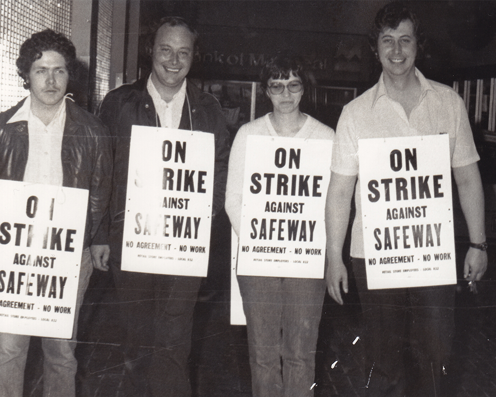 Black and white image of four picketers wearing "on Strike against Safeway" signs. 