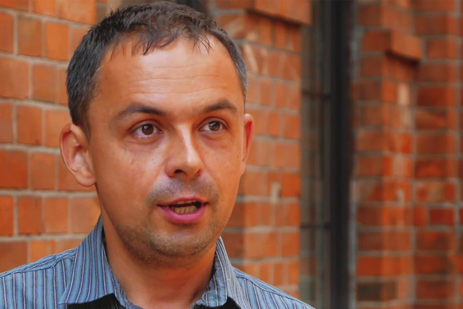 Close up photo of Dr. Andriy Zayarnyuk with brick background
